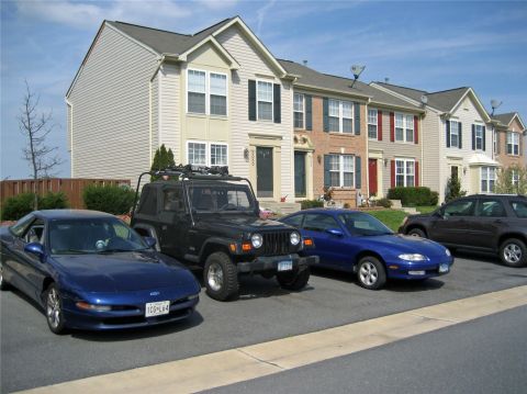 1993 Ford Probe - A blue 1993 Ford Probe is parked in a driveway alongside other vehicles and townhouses.