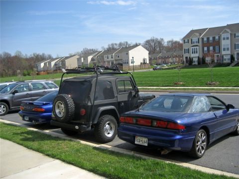 1993 Ford Probe - Two blue 1993 Ford Probes are parked next to a black Jeep Wrangler in a residential area.