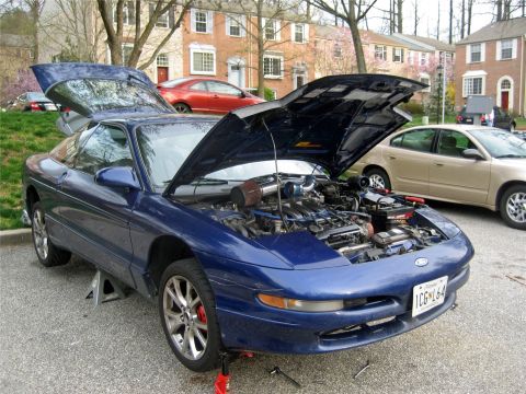 1993 Ford Probe - A blue 1993 Ford Probe is parked with its hood and trunk open, revealing the engine and interior, while supported by jack stands.
