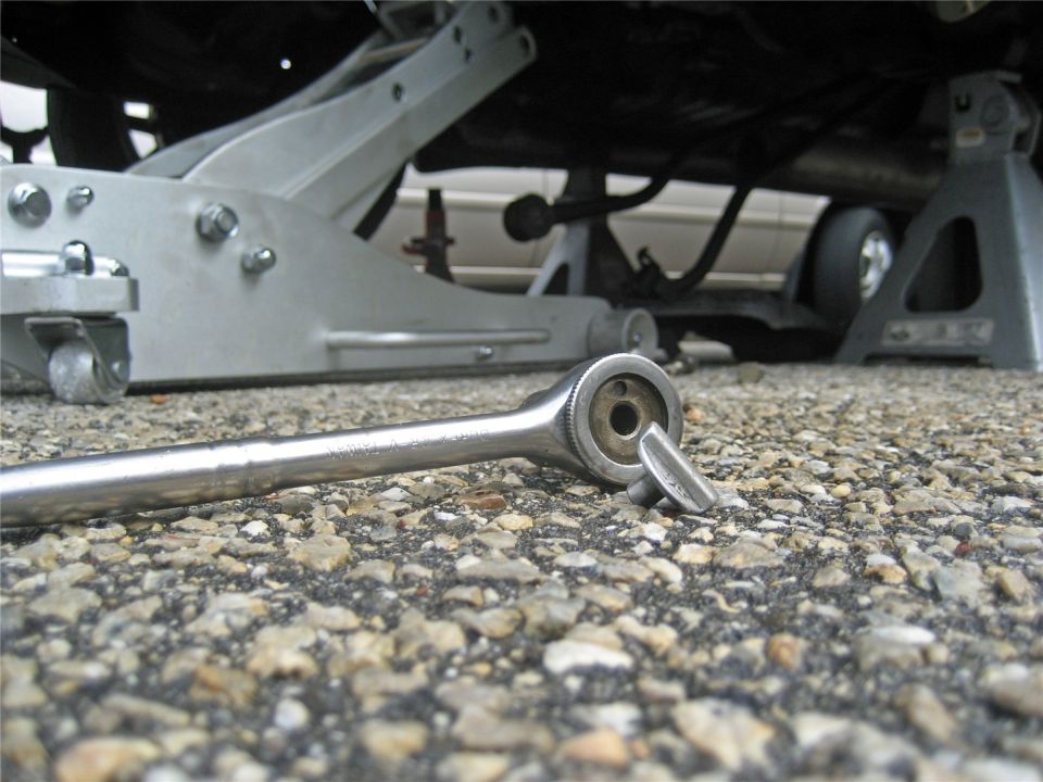 Ratchet and jack stands under a vehicle, with a glimpse of the car's undercarriage