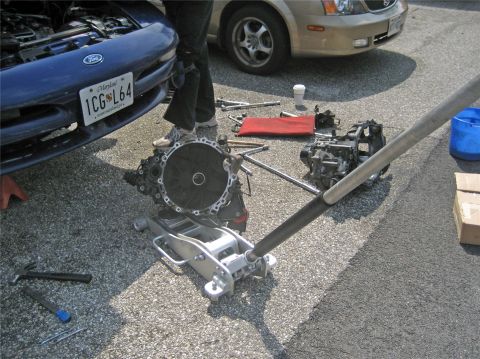 1993 Ford Probe - Removing the transmission from a 1993 Ford Probe, with a second vehicle visible in the background.