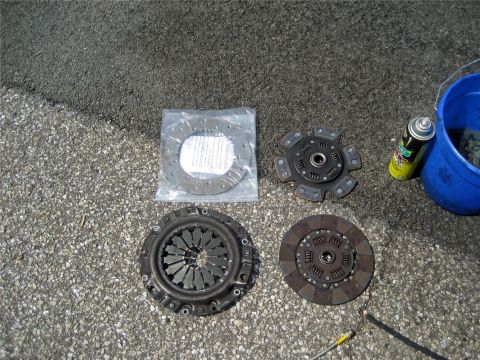 1993 Ford Probe - Clutch components are arranged on a paved surface, with a spray can and bucket nearby.