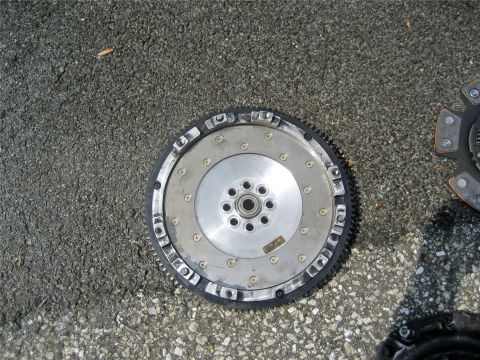 1993 Ford Probe - A clutch and flywheel assembly is shown on an asphalt surface, with a second clutch part visible in the background.