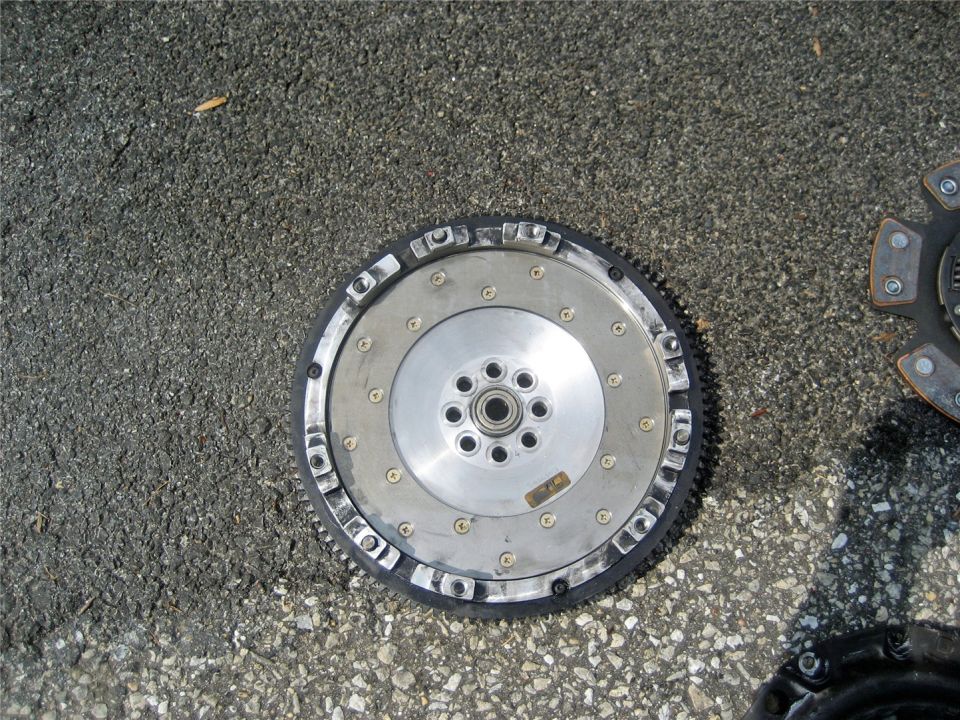 clutch and flywheel assembly on asphalt, with another clutch visible to the right