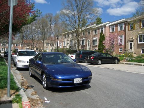 1993 Ford Probe - A blue 1993 Ford Probe is parked on a residential street next to other vehicles.