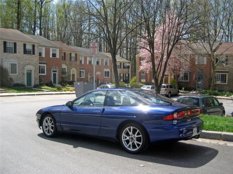 1993 Ford Probe - A blue 1993 Ford Probe is parked on a residential street with townhouses and trees.
