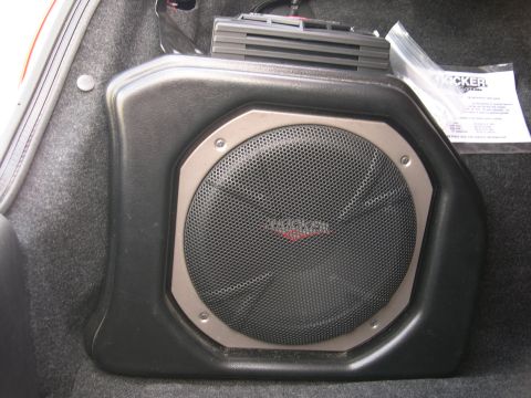1997 Ford Probe - Kicker subwoofer enclosure installed in a car's trunk area, with manual visible.
