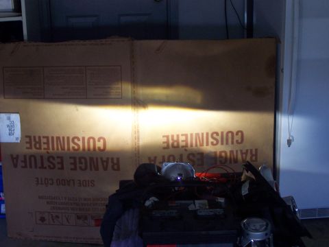 1993 Ford Probe - A bright headlight beam illuminates a large cardboard box with French text reading 'RANGE ESTUFA CUISINIERE'.