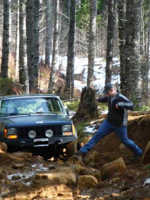 2005 Jeep Wrangler - A dark green Jeep Cherokee XJ with round auxiliary lights mounted in its grille and a steel front bumper with D-ring shackles sits on a mud…