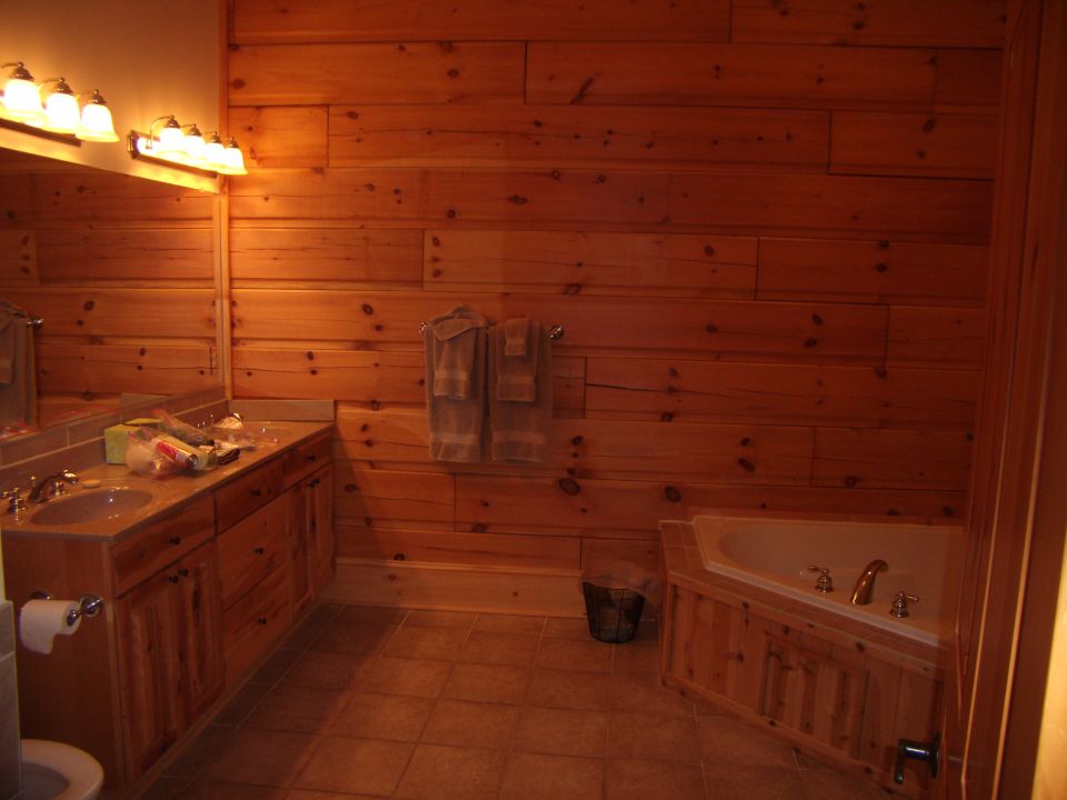 Bathroom with wood paneling, double vanity, and corner tub