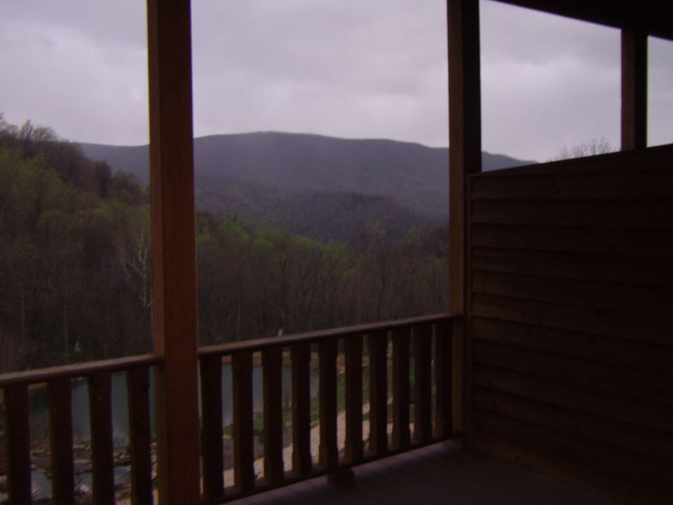 View of mountains and trees from a wooden porch with a railing