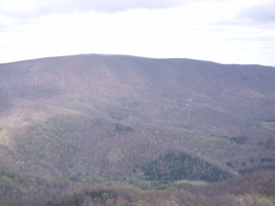 Distant mountains under a cloudy sky, with a few small structures visible on a slope