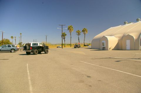 1986 Ford Bronco - A black and white Ford Bronco is parked in a lot next to a large tent structure.