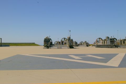 1986 Ford Bronco - Multiple landing craft air cushions are parked on a paved area under a clear blue sky.