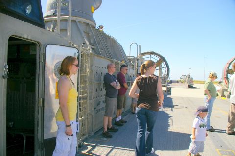 1986 Ford Bronco - A group of people are gathered on the deck of a large hovercraft, with the open sea visible in the distance.