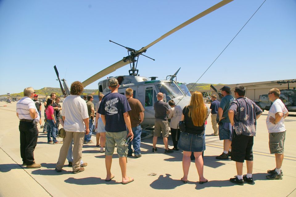 Gray helicopter on tarmac with people gathered around, viewed from the front-right