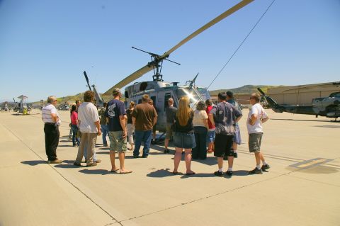 1986 Ford Bronco - A crowd observes a helicopter on a sunny day at an airfield, with other aircraft visible in the background.