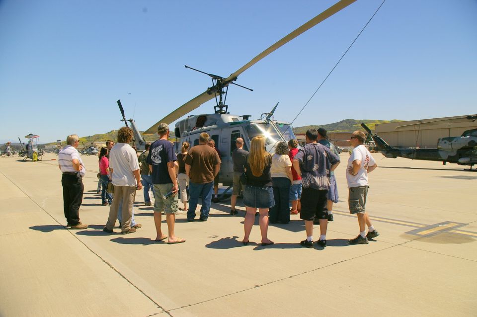 Group of people gathered around a helicopter on an airfield