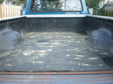 1993 Ford Bronco - The interior of a pickup truck bed shows wear and tear from use.