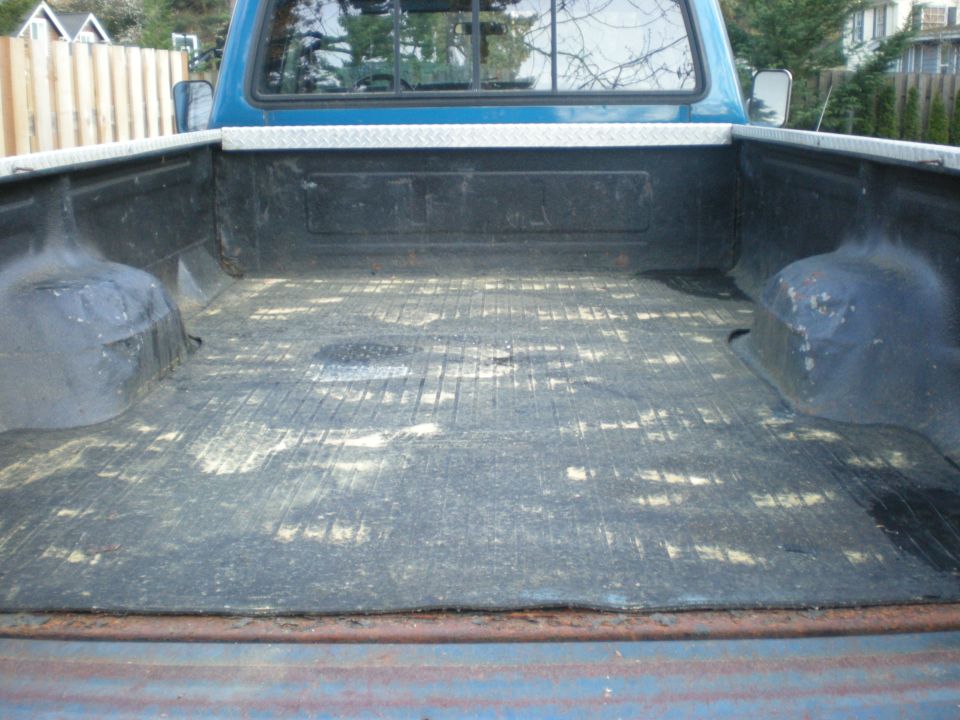 Back of a blue pickup truck bed with a diamond plate rail cap