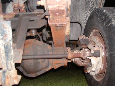 1991 Ford Bronco - Close-up view of the heavily rusted suspension and drivetrain components of an older vehicle.