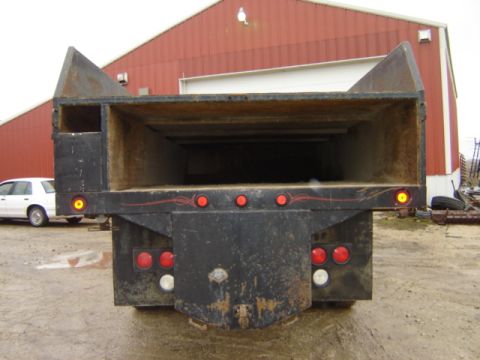 1992 Ford Bronco - Rear view of a dump truck bed with a white sedan visible to the side.