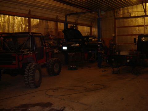 1992 Ford Bronco - Garage scene with a custom off-road vehicle and another car on a lift.