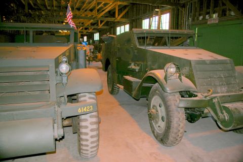 1986 Ford Bronco - Two military half-track vehicles are parked side-by-side inside a building.