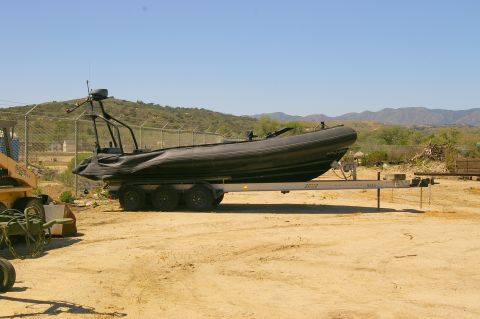1986 Ford Bronco - Inflatable boat on a trailer parked in an outdoor area with hills in the background.