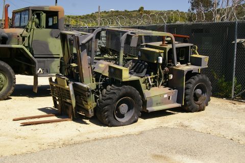1986 Ford Bronco - A camouflage military forklift with visible forks sits next to a larger camouflage truck.