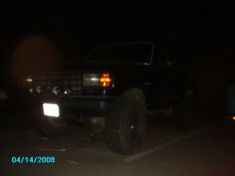 1990 Ford Bronco - A black Ford Bronco is parked at night, illuminated by its headlights and aftermarket lights.