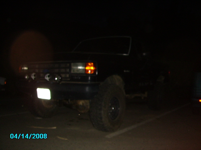 Black Ford Bronco with aftermarket lights and large tires parked at night