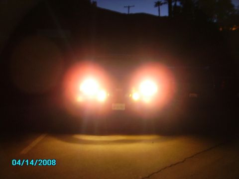 1990 Ford Bronco - The rear of a vehicle is illuminated by its headlights at dusk.