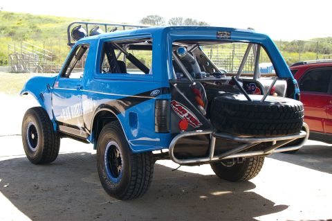 1986 Ford Bronco - Modified 1986 Ford Bronco with off-road tires and spare tire carrier, seen next to a red SUV.