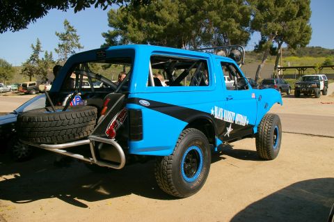 1986 Ford Bronco - A modified blue SUV with off-road tires and a spare tire carrier is parked outdoors.