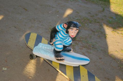 1986 Ford Bronco - Monkey figurine on a skateboard with blue and white surfboard detail.
