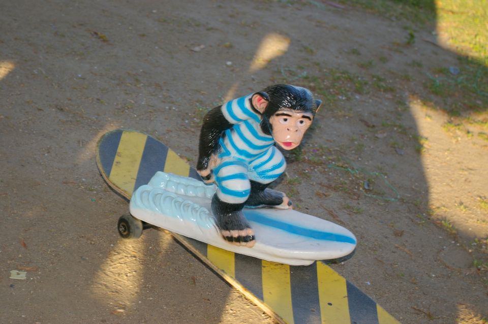 Monkey figurine wearing a striped shirt and pants, riding a skateboard with yellow and black stripes
