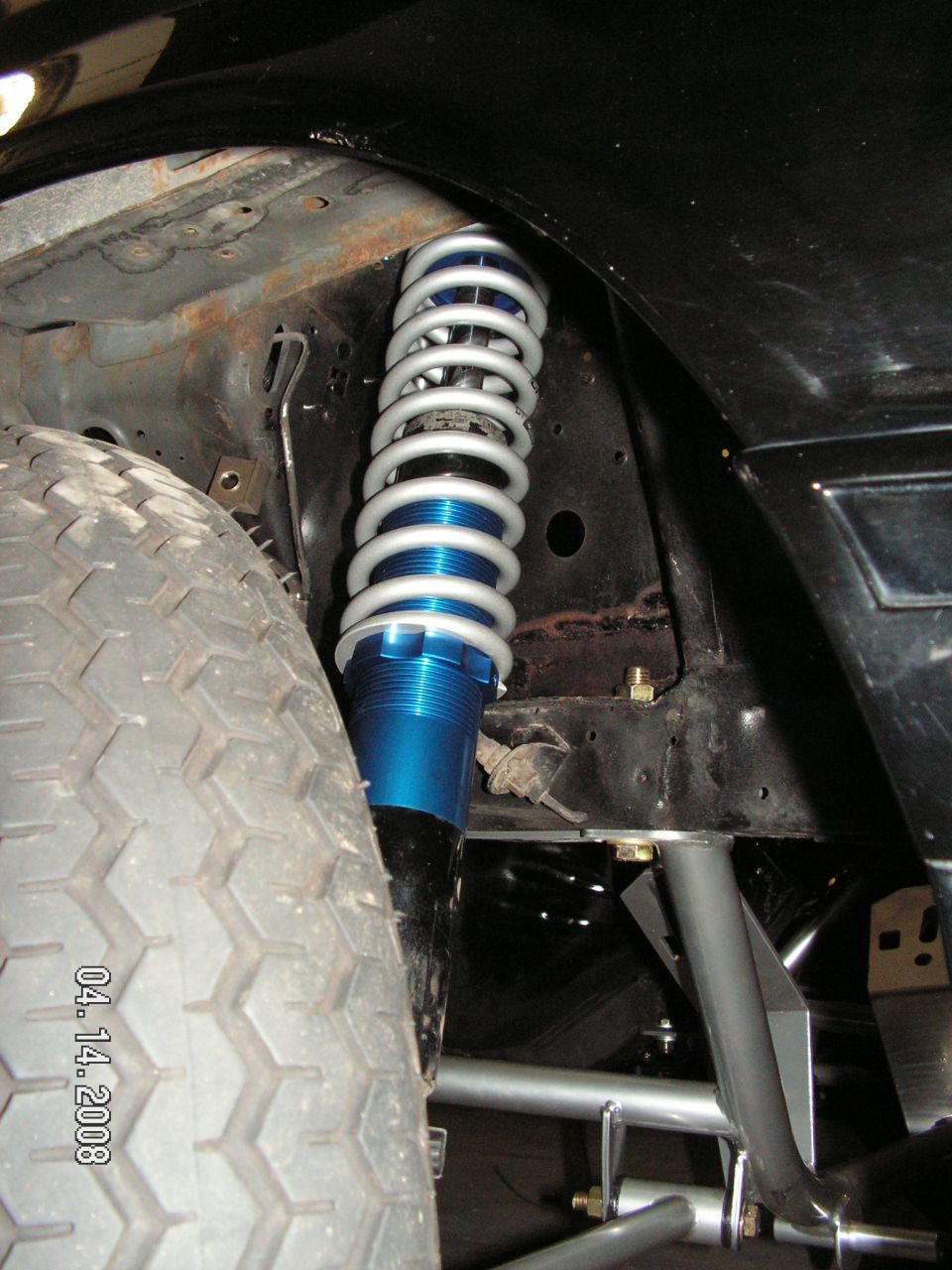 Aftermarket blue and silver coilover shock absorber mounted near a tire