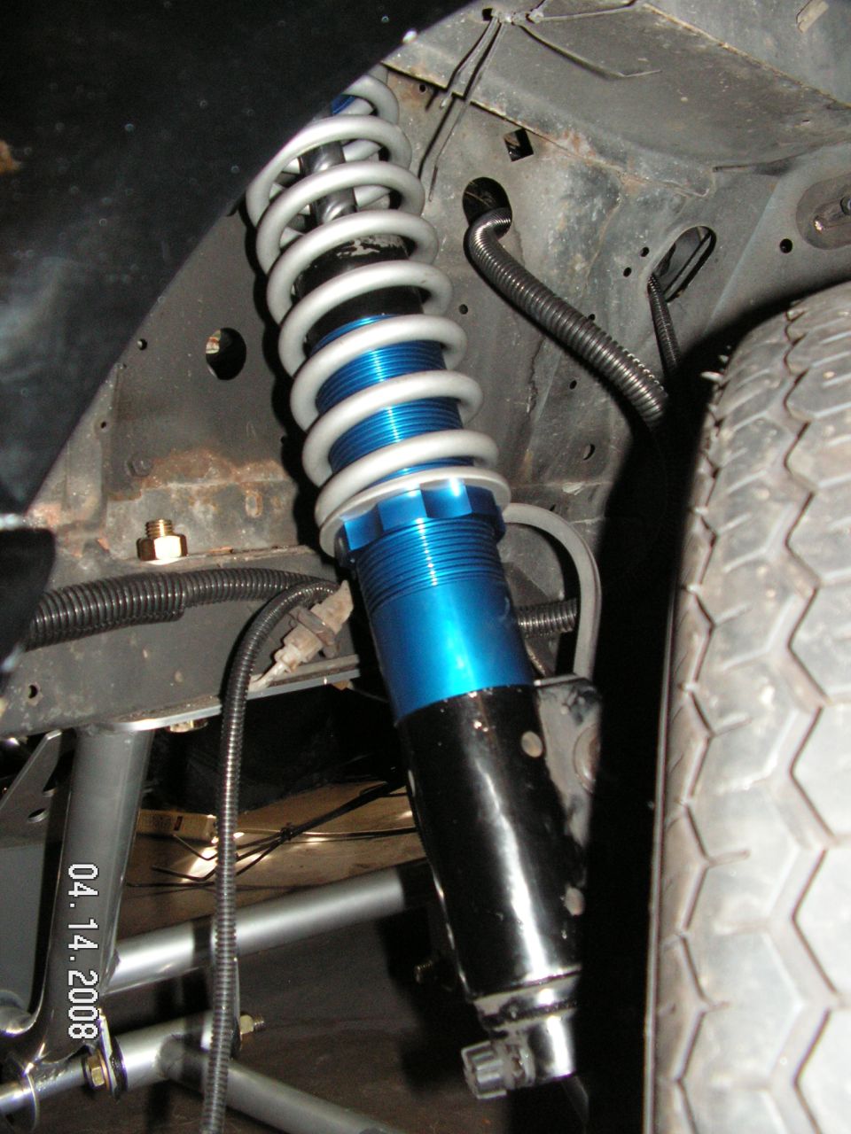Close-up of a blue and silver aftermarket coilover shock absorber on a vehicle's suspension