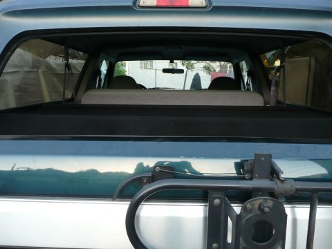 1991 Ford Bronco - The interior of a Ford Bronco is visible through the rear window, with seats and cargo space apparent.