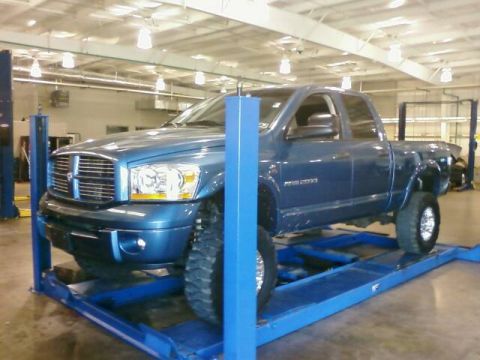 2006 Dodge 2500 - A blue 2006 Dodge 2500 pickup truck is elevated on a blue hydraulic lift in a garage.