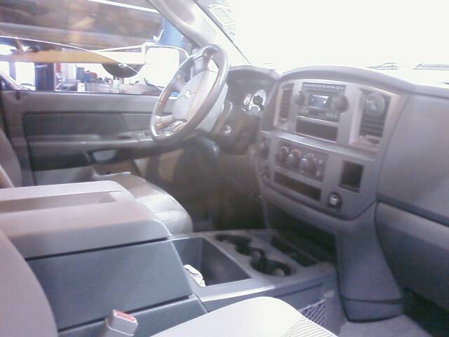 Gray interior of a Dodge pickup showing steering wheel, dash, radio, and center console cup holders