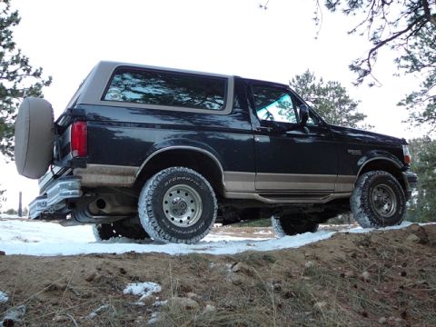 1996 Ford Bronco - The rear-mounted spare tire is visible on this dark-colored Ford Bronco.