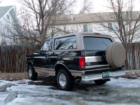 1996 Ford Bronco - Rear view of a 1996 Ford Bronco with a spare tire cover, parked outdoors in winter.