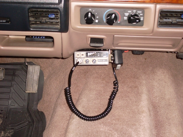 CB radio with microphone hanging below dashboard, next to pedals