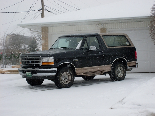 Black and tan 1996 Ford Bronco parked in snow, front 3/4 view
