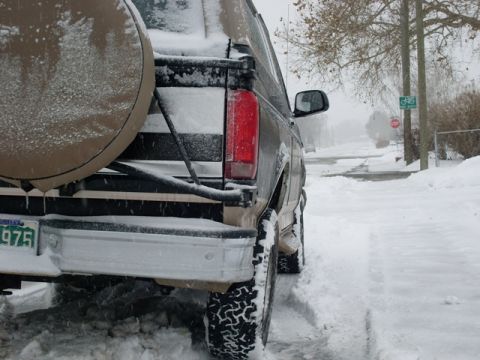 1996 Ford Bronco - A tan SUV with a spare tire mounted on the rear is parked in the snow, with a license plate reading '975'.