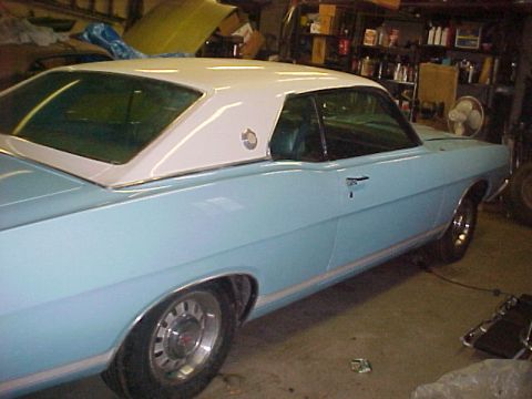 1969 Ford Torino - A light blue 1968 Ford Torino coupe with a white roof is parked in a garage, with shelves and a fan visible in the background.