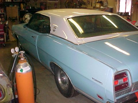 1969 Ford Torino - The rear quarter panel of a light blue 1969 Ford Torino coupe shows the distinctive taillight design and 'Torino' badging.