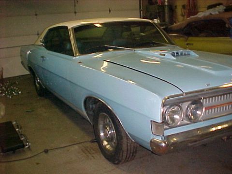 1969 Ford Torino - A light blue coupe with a white roof sits in a garage, showing off its front end and side profile.